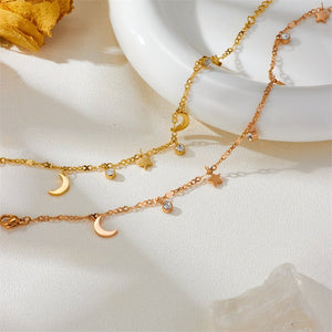 Gold bracelet with moon and star charms on a light background