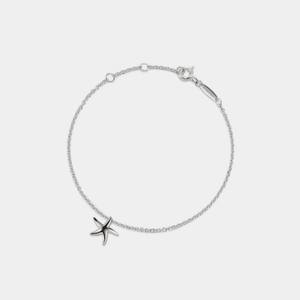 Silver bracelet with a starfish charm on a light gray background