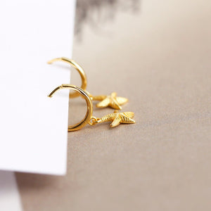 A pair of hoop earrings with starfish charms attached, plated in gold, displayed against a white background.