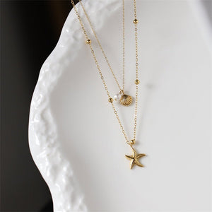Gold necklace with star pendant on a white textured surface