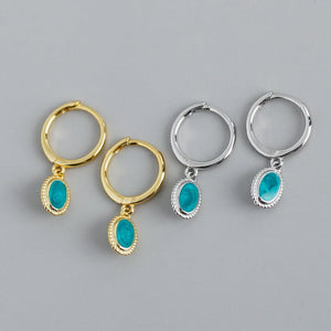 Two pairs of hoop earrings with turquoise stones on a gray background