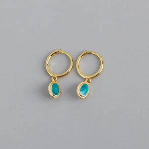 A set of oval drop hoop earrings with a starry night enamel design in blue and green, available in gold and silver finishes.