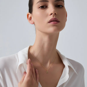 Woman wearing a gold sun necklace with a white shirt on a plain background