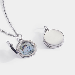 Sterling silver round locket necklace shown open and closed, featuring a smooth polished exterior and a photo insert inside, displayed on a delicate chain against a white background.