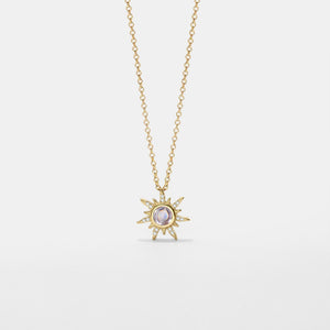 Gold necklace with a sun-shaped pendant on a light gray background