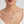 Silver necklace with a round locket featuring a sun face design, worn on a delicate chain on a model’s neck.