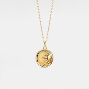 Gold necklace with a round locket feature a sun face design on a light gray background