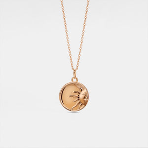 Rose gold necklace with a round locket feature a sun face design on a light gray background