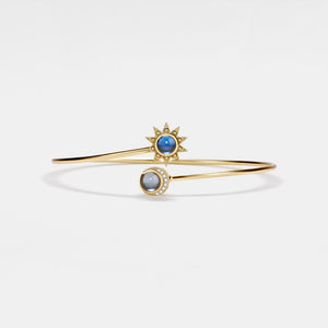 Gold bracelet with blue and gray gemstones on a light gray background