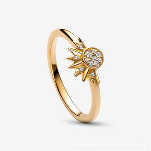 A gold-colored ring featuring a sun motif with rays extending outward, set with small cubic zirconia stones.