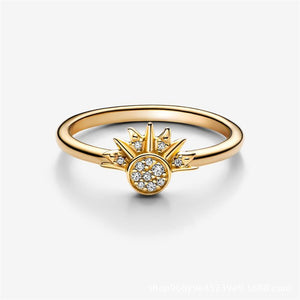 A gold-colored ring featuring a sun motif with rays extending outward, set with small cubic zirconia stones.