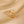 Gold ring with floral design on a beige fabric background