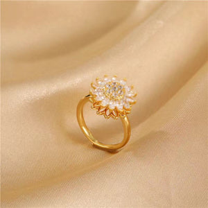 Gold ring with floral design on a beige fabric background