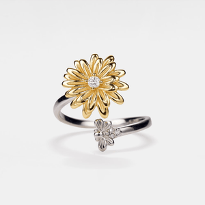 Gold and silver flower-shaped ring with gemstones on a white background