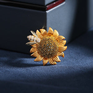 Gold sunflower-shaped brooch with a dark blue background
