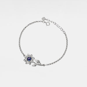 Silver bracelet with silver sunflower design featuring a projection gemstone on a white background