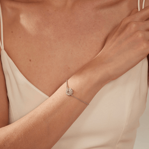 A model wearing a silver bracelet with a sunflower-shaped charm and projection gemstone