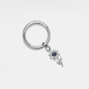 Silver projection keychain with a silver sunflower charm on a light gray background