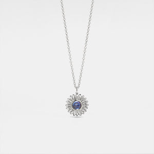A white gold-plated sterling silver necklace with a sunflower charm and a central projection stone, displayed on a white background.