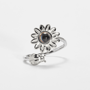 Silver sunflower-shaped ring with a central projection gemstone on a white background