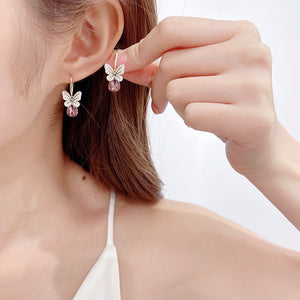 Butterfly-shaped earrings being worn by a person with a plain background