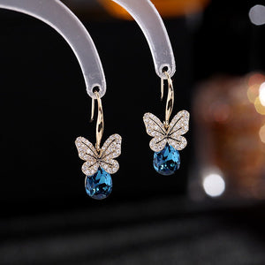Butterfly earrings with blue gemstones on a dark background