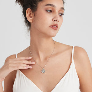 Sterling silver round locket necklace with a “Little Prince” engraved design and star detail, worn on a delicate chain on a model’s neck.