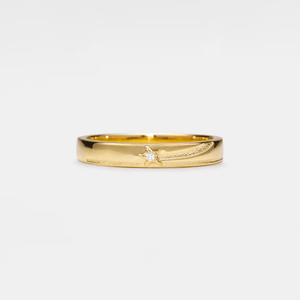 Gold band ring with a shooting star pattern on a white background