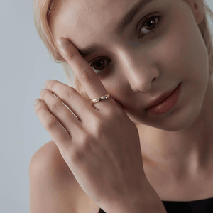 Woman wearing a gold band ring with a shooting star pattern on a white background