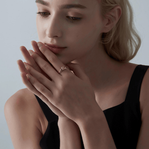 Woman wearing a gold vine ring with a pink heart-shaped gemstone on a white background
