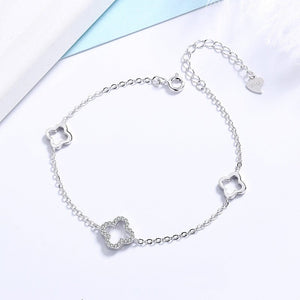 Silver bracelet with clover-shaped charms on a light blue and white background