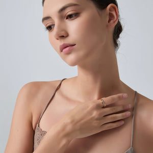 Woman wearing a beige bralette with a plain background