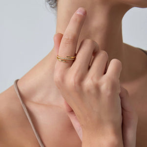 Close-up of a hand wearing a gold ring on a neutral background