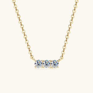 Gold necklace with a bar pendant featuring blue gemstones on a white background