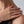 Close-up of a hand wearing a diamond ring on a neutral background