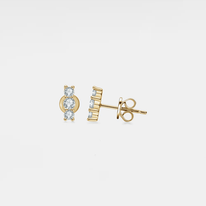 Gold earrings with gemstones on a light gray background