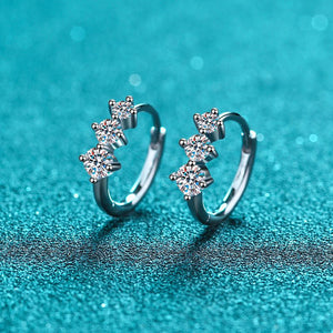 Pair of silver earrings with clear gemstones on a teal background
