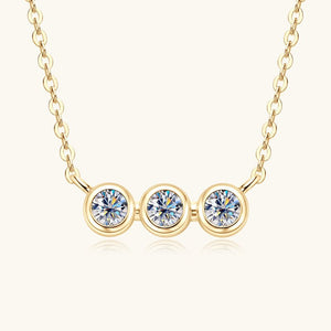 Gold necklace with three round diamonds on a white background
