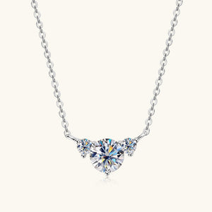 A moissanite charm necklace with a three-stone design, set in a gold-colored mounting, attached to a gold-plated chain.