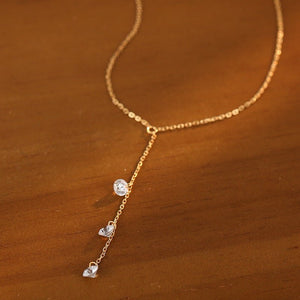 Gold necklace with heart-shaped pendants on a wooden surface