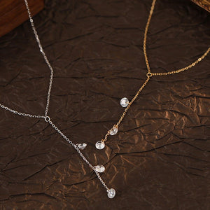 Two necklaces, one gold and one silver, on a brown textured surface.