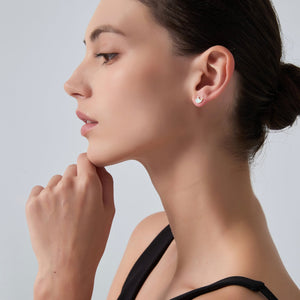 Close-up of a woman wearing diamond earrings with a neutral background