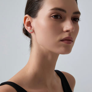 Close-up of a woman wearing a small earring on a plain background