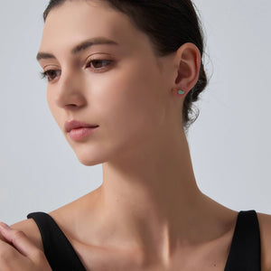 Close-up of a woman wearing a small earring on a plain background