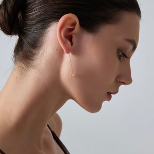 Close-up of a woman wearing a gold earring on a plain background