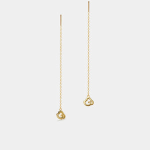 Gold earrings with a heart-shaped pendant on a light gray background