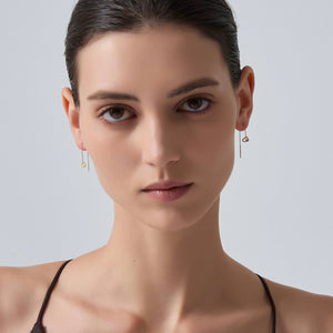 Close-up of a woman wearing gold earrings against a light gray background
