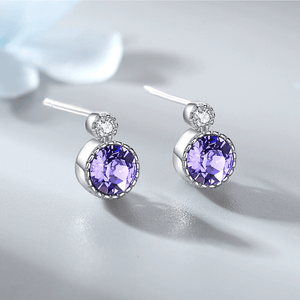 Silver earrings with purple gemstones on a light gray background