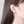 Close-up of an ear wearing a blue gemstone earring with a neutral background