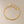Gold bracelet with a small cross charm on a beige background